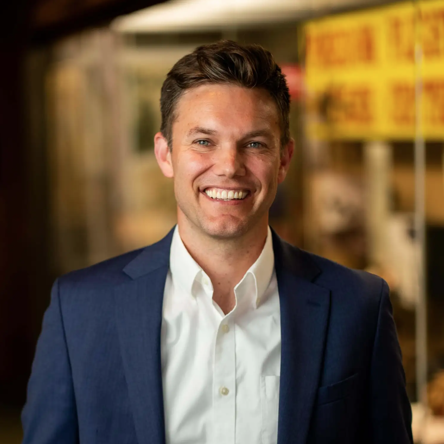 Matthew Vriesman in a white collared shirt with a navy blue suit jacket