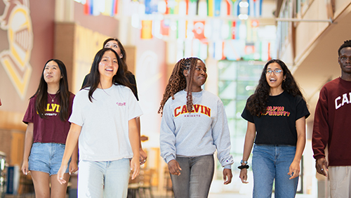Calvin students walking in the Spoelhof Fieldhouse Complex under the international flags
