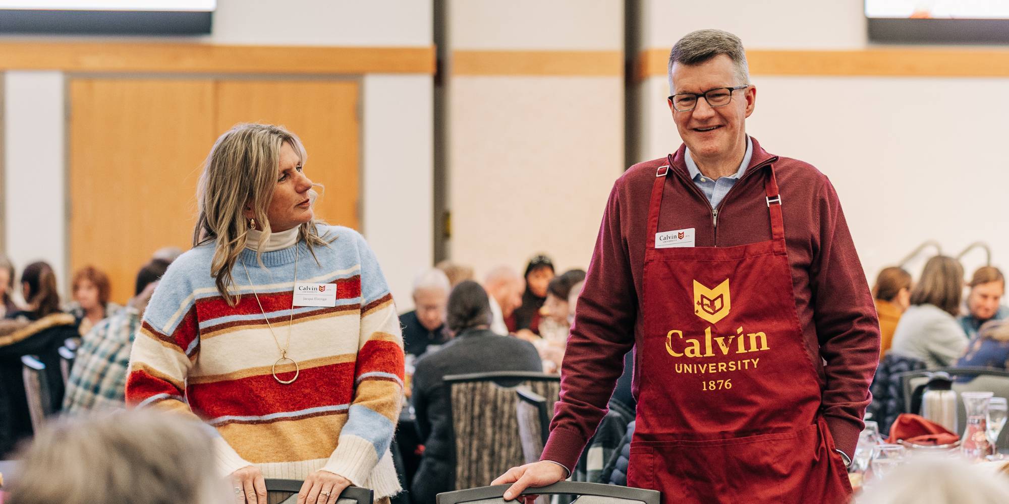 Jacqui and Greg Elzinga visit tables of faculty and staff at Calvin University's Thanksgiving meal.