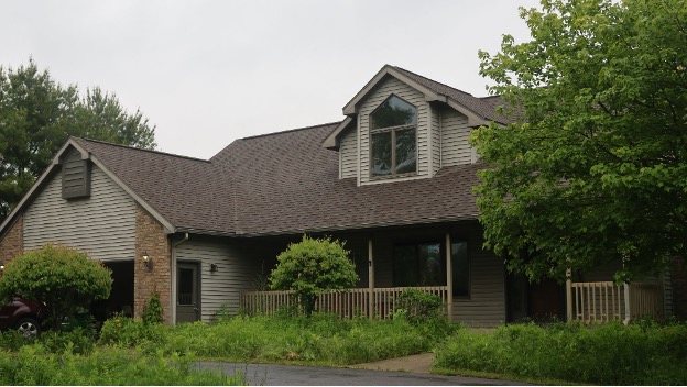 A two-story house surrounded by trees.