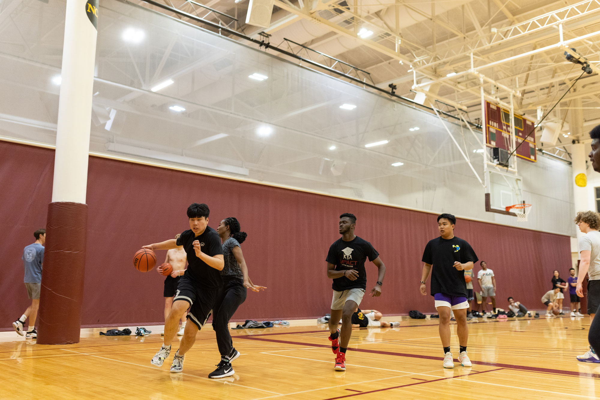 A group of students play co-ed intramural basketball in an indoor gym.