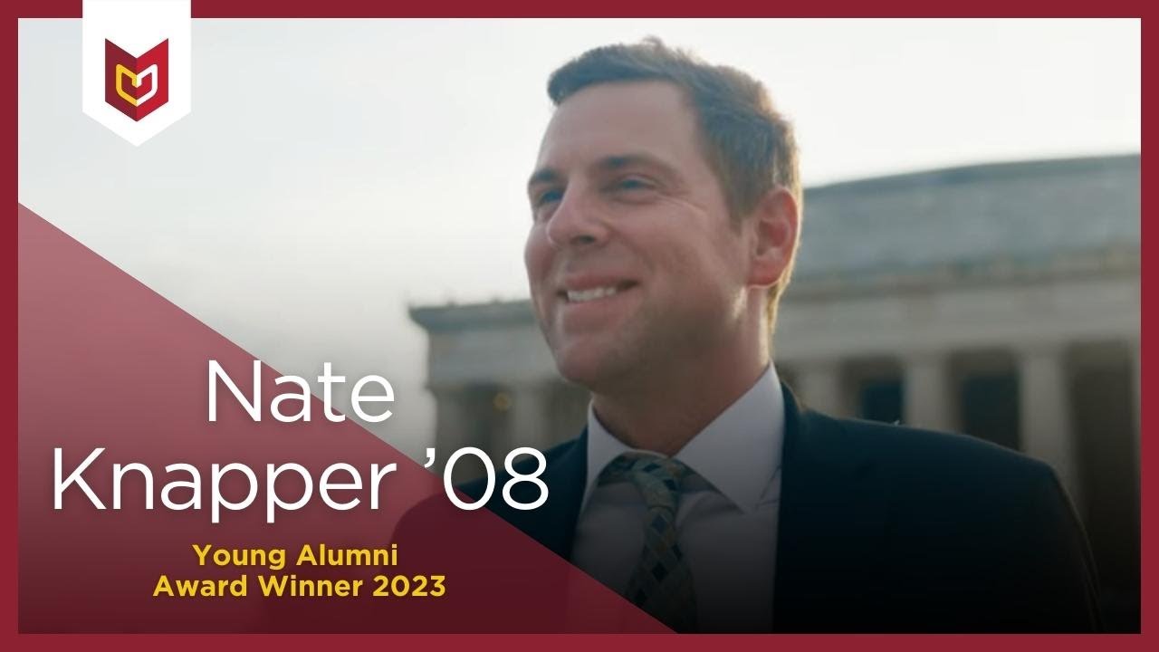 Nate Knapper stands in front of a government building smiling.