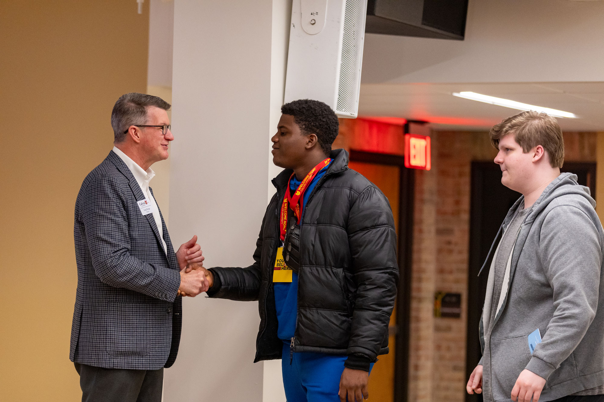 President Elzinga shakes hands with new spring transfer students at a transfer dinner event.