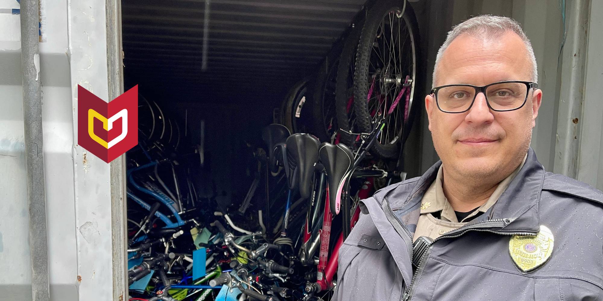 Tyson Moore stands in police uniform in front of stack of bikes