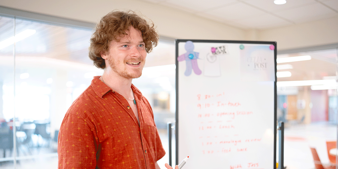 Luke Harlow stands by a whiteboard.