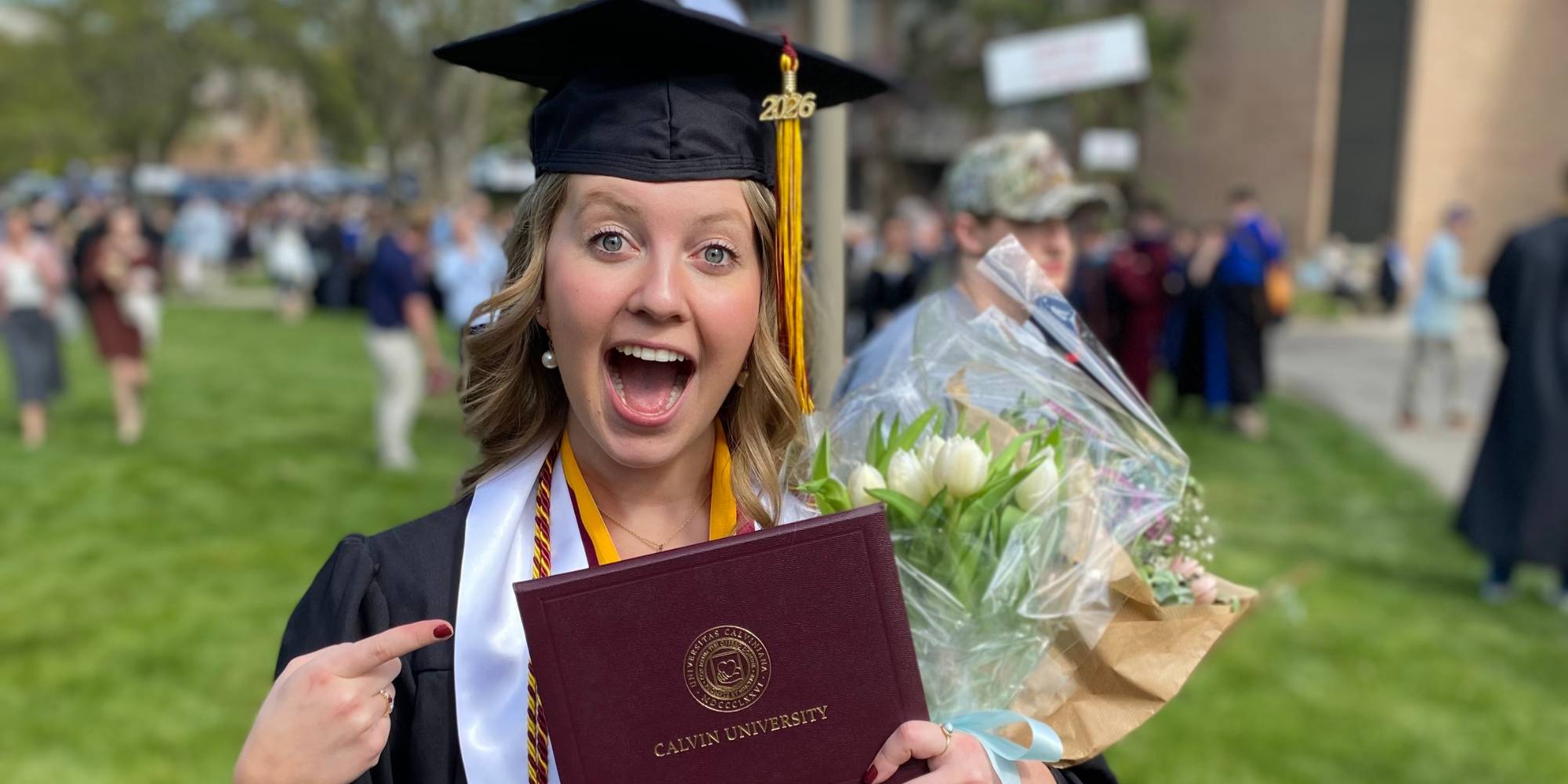 Meg Pheifer holding diploma from Calvin University