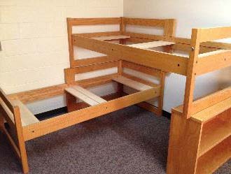 A single bed stacked on another single at a 90° angle, using the side rails of both, with the end of the upper bed supported by a bookcase.