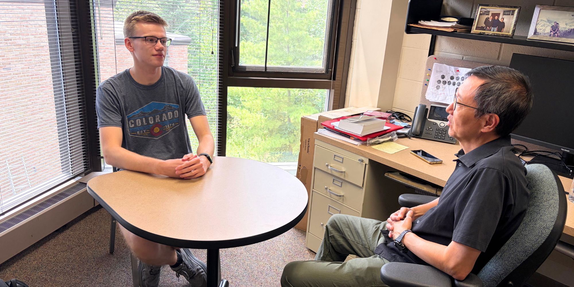 Landon Faber talks with Professor Rocky Chang in his office.