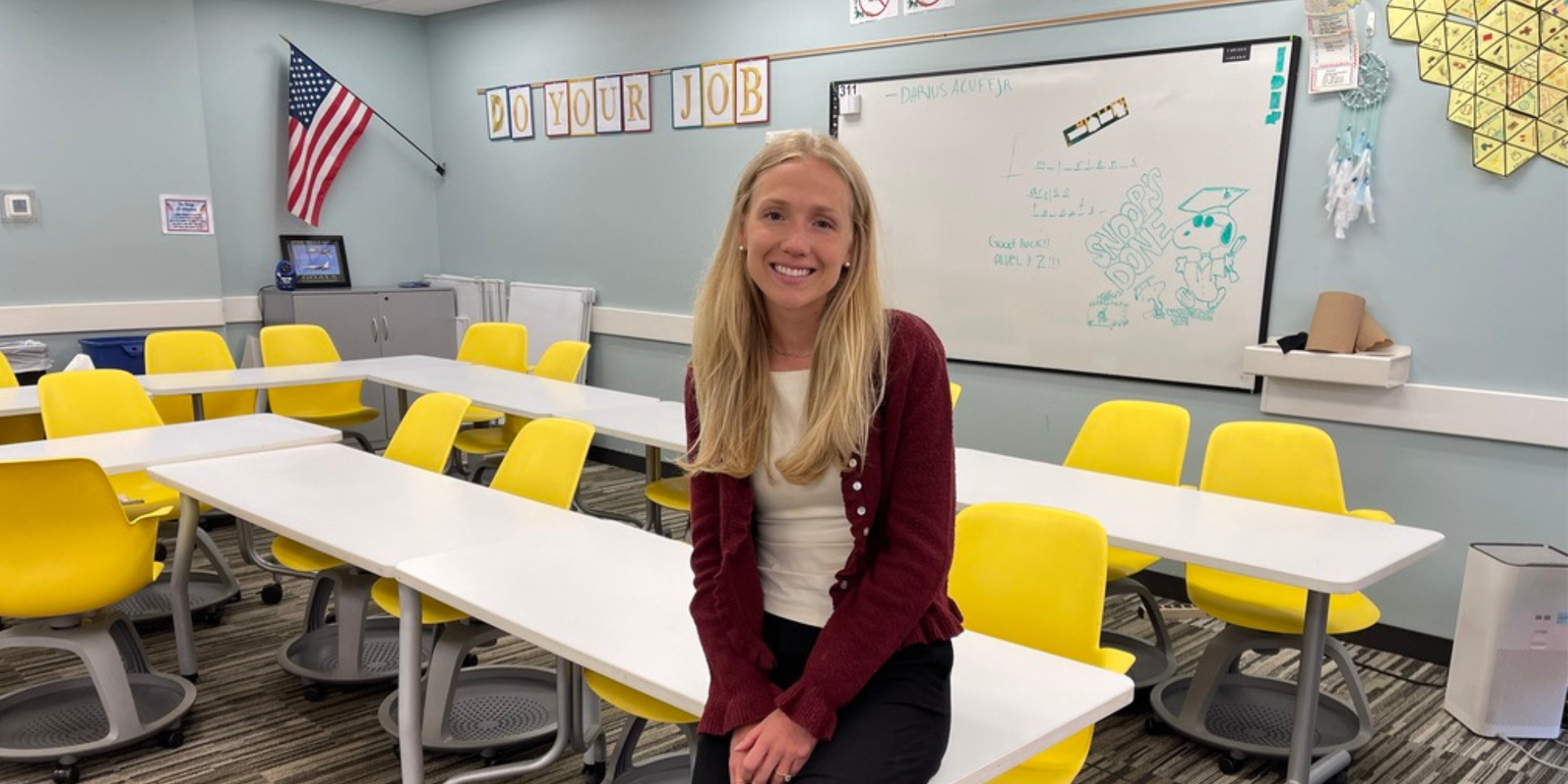 Maaike Bult leaning on a table of desks at West Aviation Academy