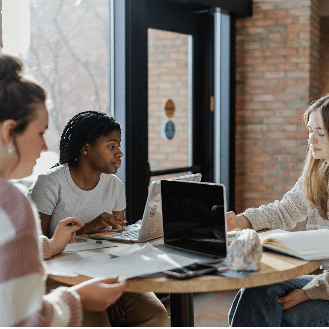 3 female students sitting a table for group work. 
