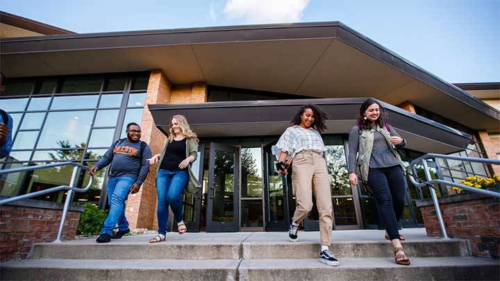 Four students walking down a staircase out the entrance to a university building