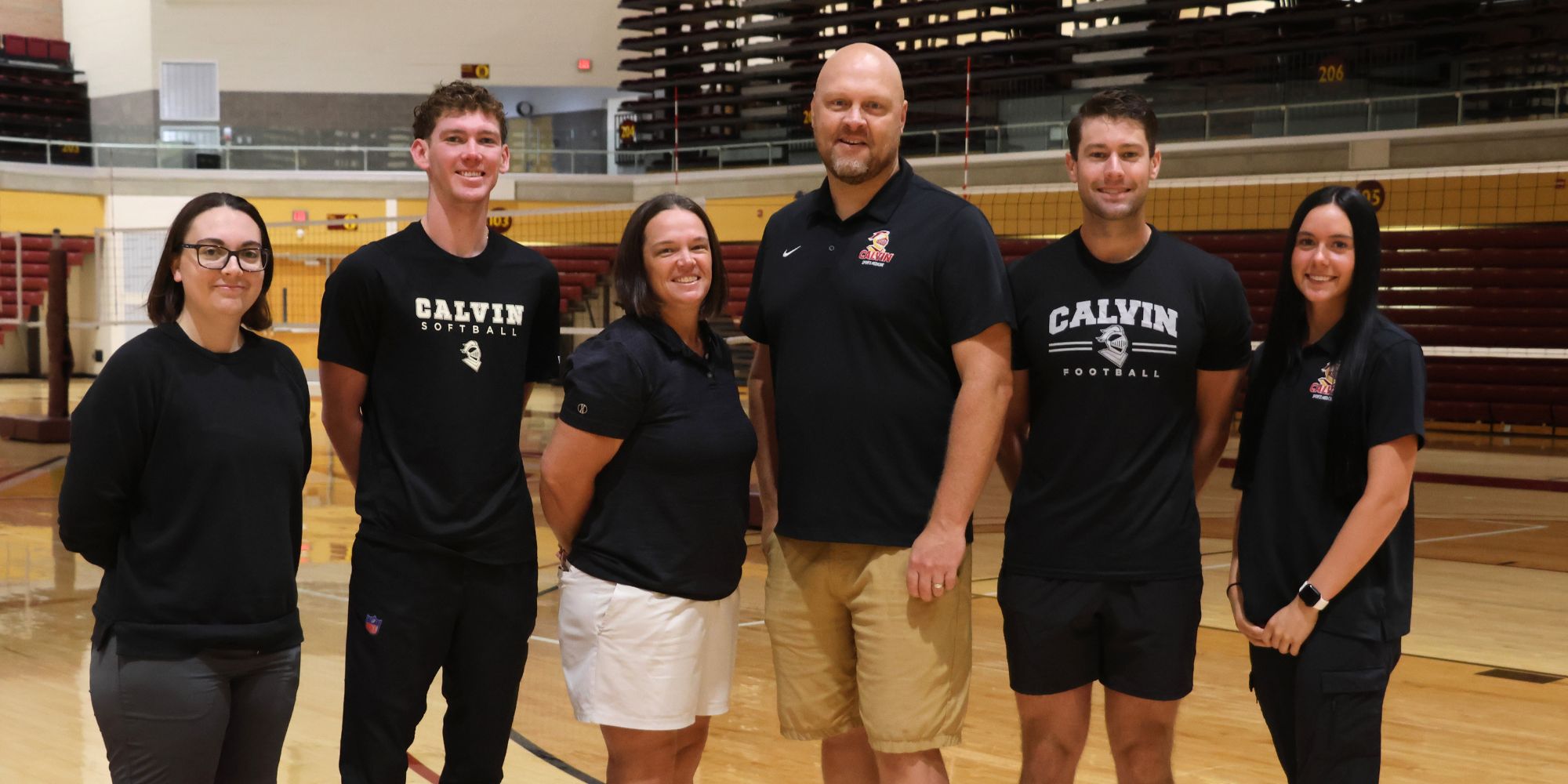 Five people stand camera aware on the court inside Van Noord Arena.