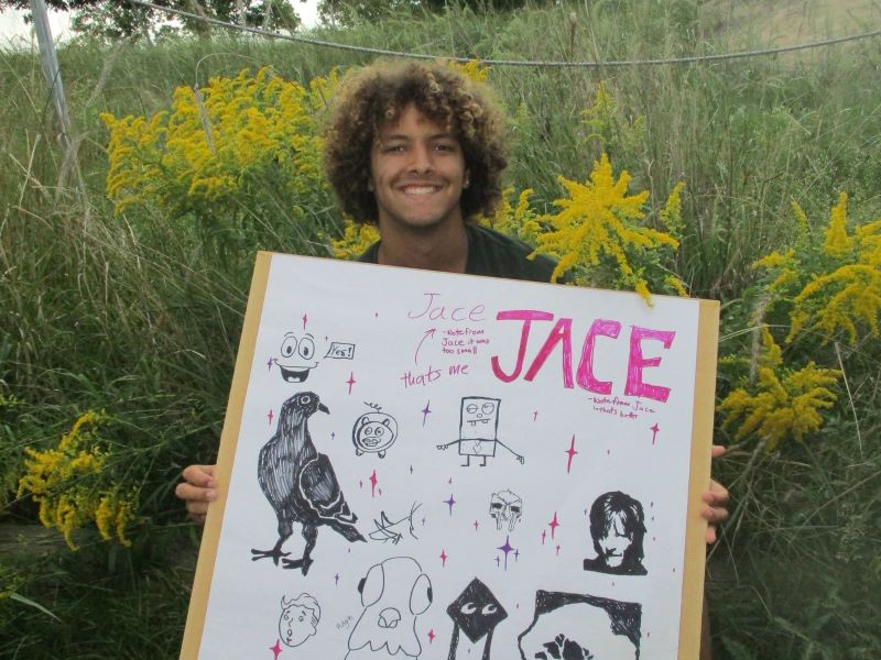A FYRES mentor holding a sign that says: "Jace"