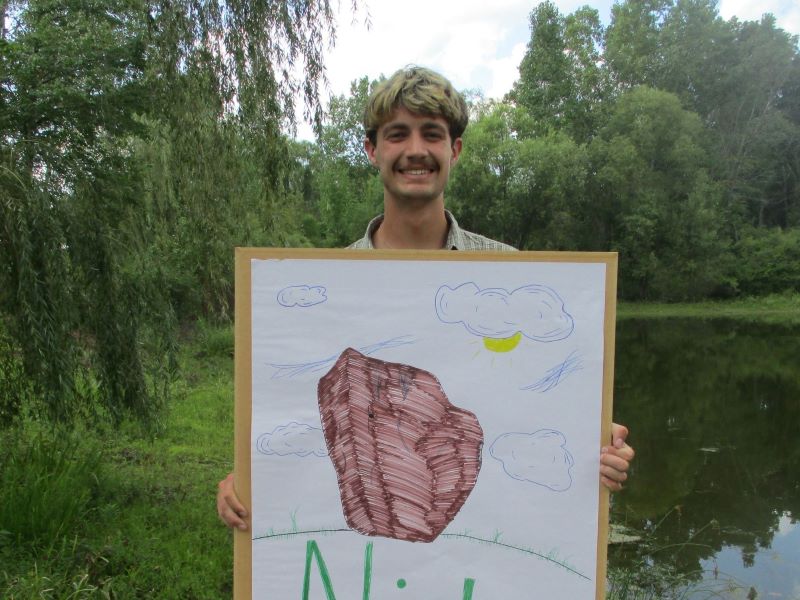 A FYRES mentor holding a sign that says: "Nick"