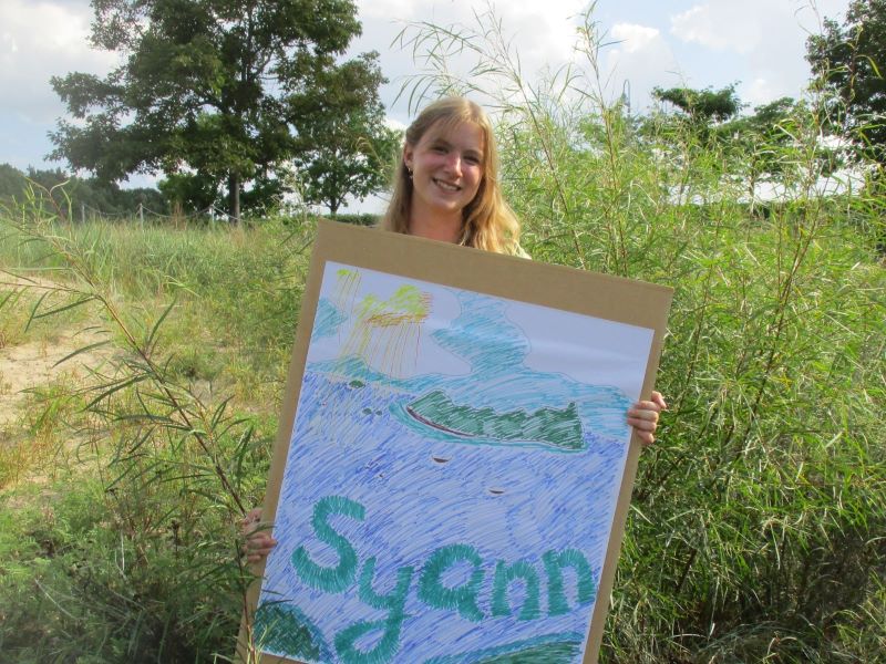 A FYRES mentor holding a sign that says: "Syann"