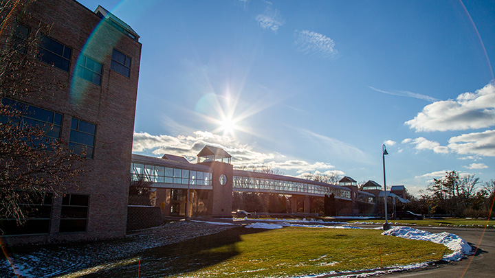 A wide shot of a covered bridge in winter that connects two sides of campus over a busy road.