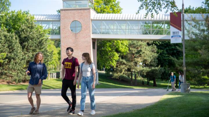 Three students walk beneath the overpass on Calvin's campus during a tour.