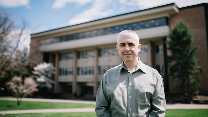 David Smith stands on the Commons Lawn with the Hekman Library in the background.