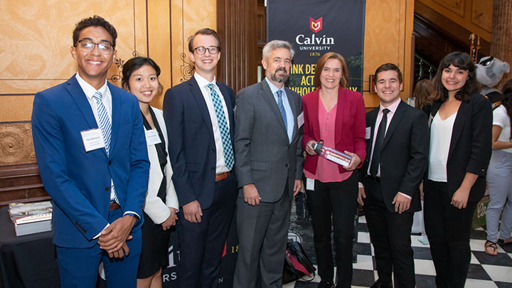 Five students and Calvin's president pose in the Capitol building with a legislator.