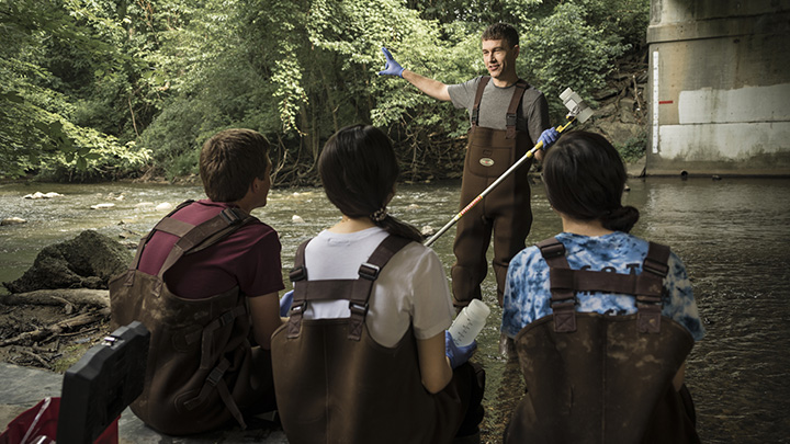 Biology professor Randall DeJong conducting research with students in Plaster Creek.