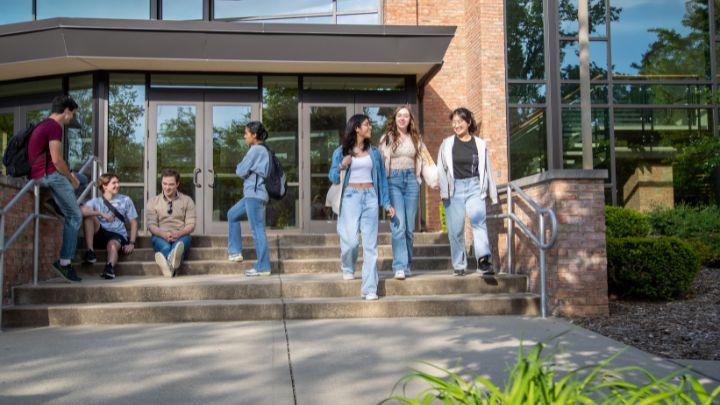 A group of students walking down steps while another group talks on the steps