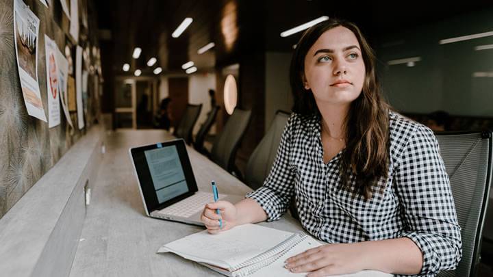 Female student sitting at desk with laptop and note pad out