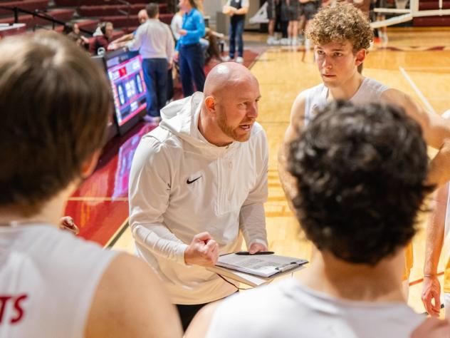 Coach Aaron Sagraves talks to his Calvin men's volleyball team in the huddle.