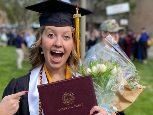 Meg Pheifer holding diploma from Calvin University