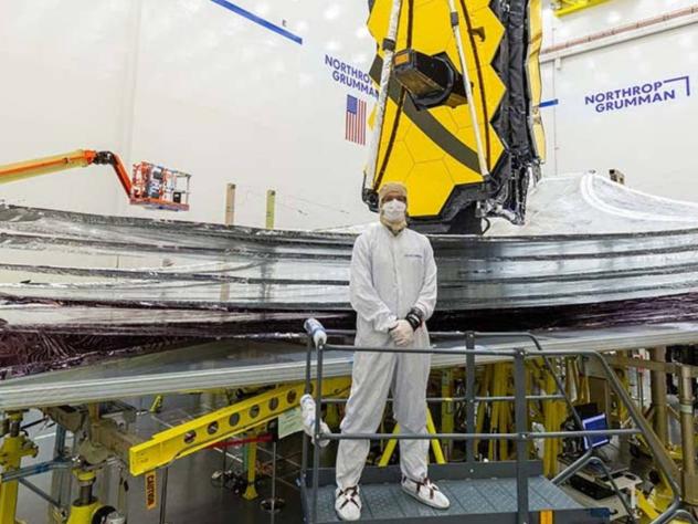 Adam Marquardt standing in the clean room in front of a telescope that's going to be launched into space.