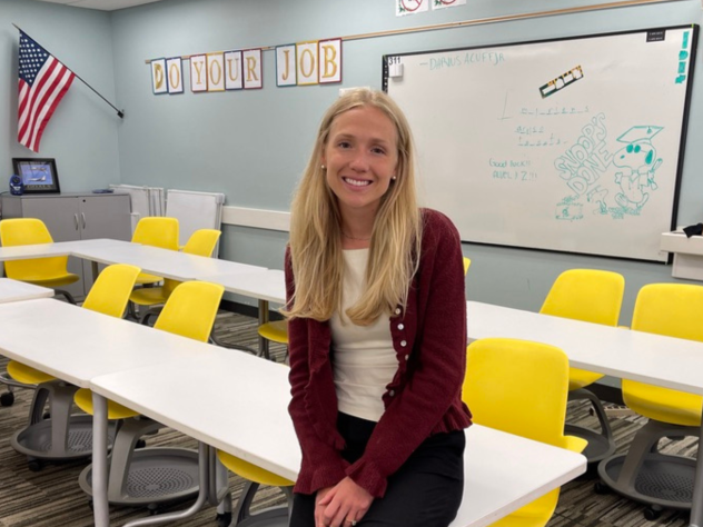 Maaike Bult leaning on a table of desks at West Aviation Academy