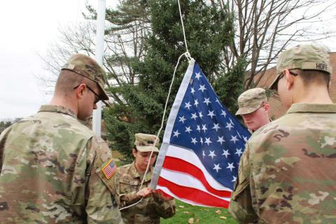 A group of Army ROTC students fold a flag in uniform on Calvin University campus.