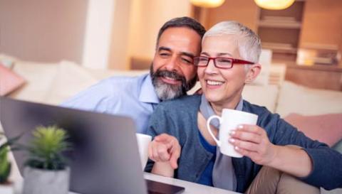 Adult male and female sitting in front of a laptop watching a webinar