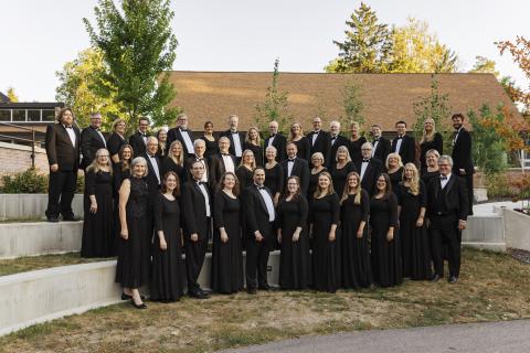 The Calvin alumni choir stands in rows, wearing formal black choral attire.