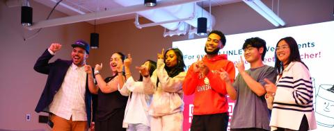 A diverse group of CISD staff and students show number 1's with their hands while posing for a group photo.