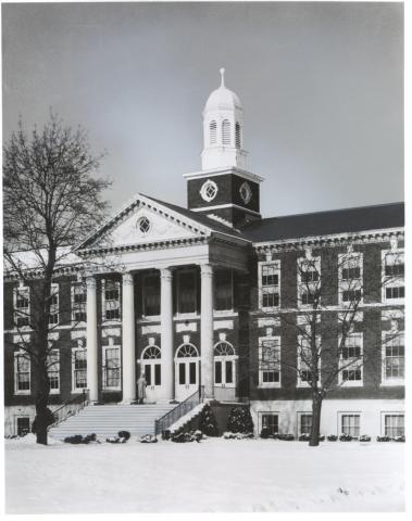An academic building with large pillars, front steps, and rows of windows.