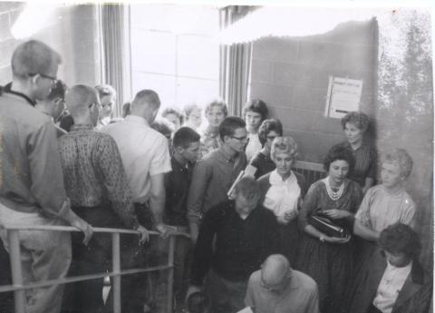 Many student walk down a full staircase, holding textbooks.