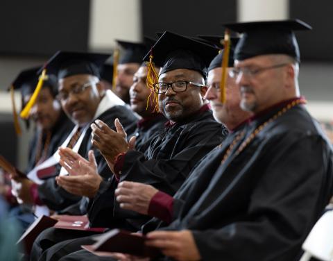 Calvin Prison Initiative graduates clap from their seats in caps and gowns during the commencement ceremony.