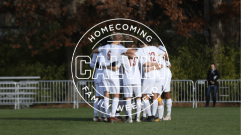 men in white soccer uniforms huddled in a circle