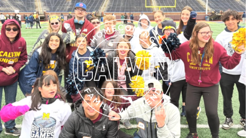 college students standing on a football field, holding pompoms