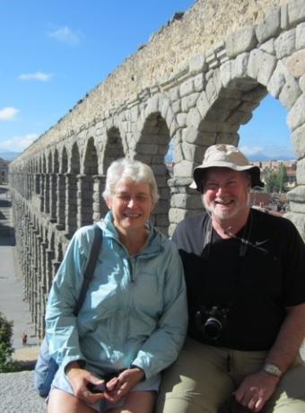 Image of professor emeritus Mark Williams and his wife sitting in front of a stone archway