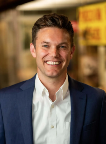 Matthew Vriesman in a white collared shirt with a navy blue suit jacket