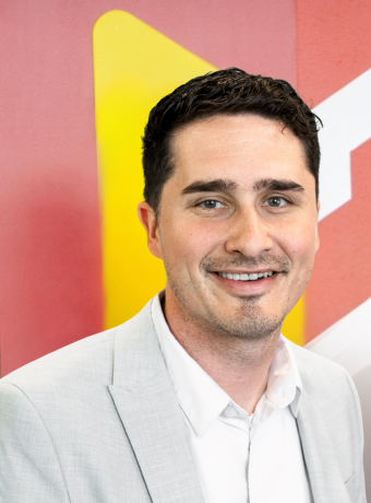 Coty Seaver smiling in front of the Calvin University emblem. 
