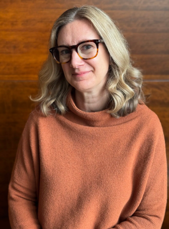 Photo of Kelli Scholten, smiling in front of brown wood background