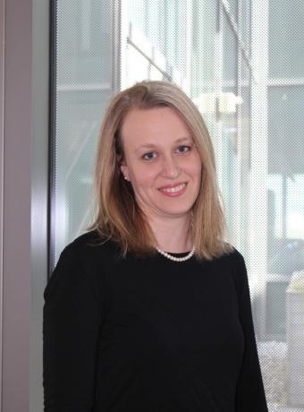 Headshot of Jenny Gill in a black shirt in front of a window