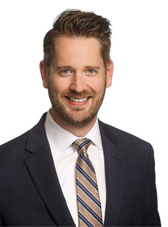 Justin Ooms in a suit and tie