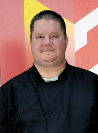 Man in with short brown hair in a Chef's coat. 