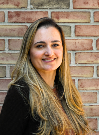 Woman with long light brown hair in front of a brick wall.