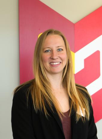 Woman in black tailored jacket with long blonde hair smiling in front of Calvin Wayfair symbol.