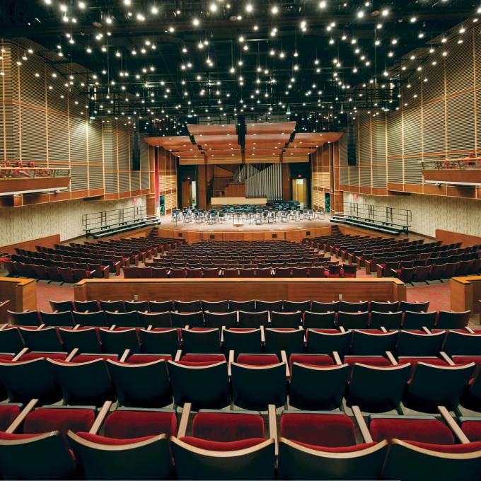 An auditorium with hundreds of hanging lights above the audience and stage.