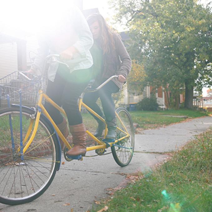 a person riding a bike on the sidewalk, sunshine coming in through the background